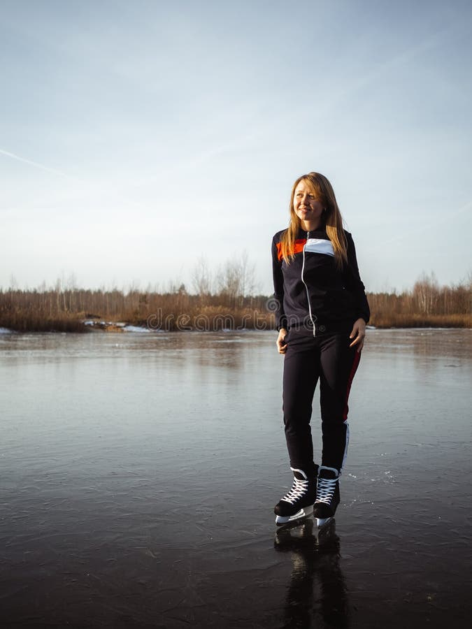 Una giovane bellissima ragazza pattinava sul ghiaccio sul ghiaccio di un lago Sullo sfondo di una foresta fotografia stock libera da diritti Una giovane bellissima ragazza pattinava sul ghiaccio sul ghiaccio di un lago Sullo sfondo di una foresta fotografia stock libera da diritti