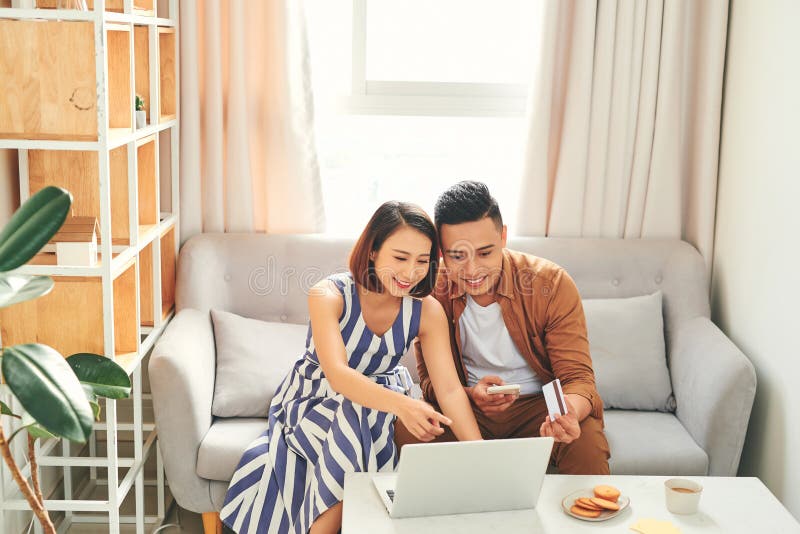 Una giovane coppia asiatica compra in linea con la carta di credito e un portatile a casa