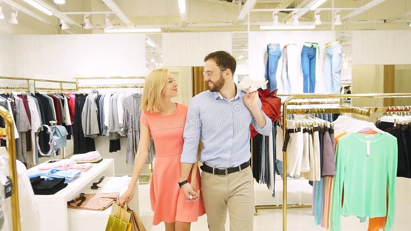 Una giovane coppia felice che fa shopping insieme vestiti in un negozio di moda. Movimento lento