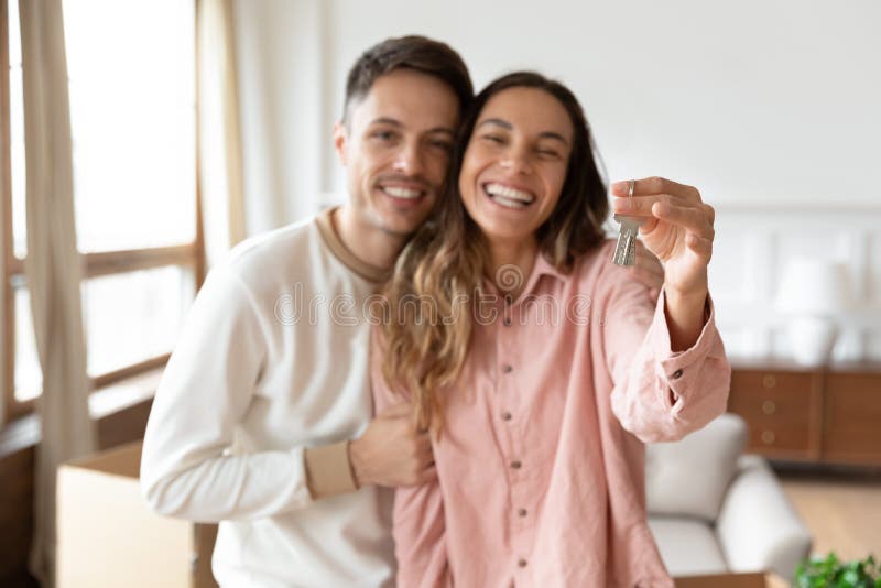 Una giovane coppia felice mostra le chiavi della casa che si trasferiscono in una nuova casa