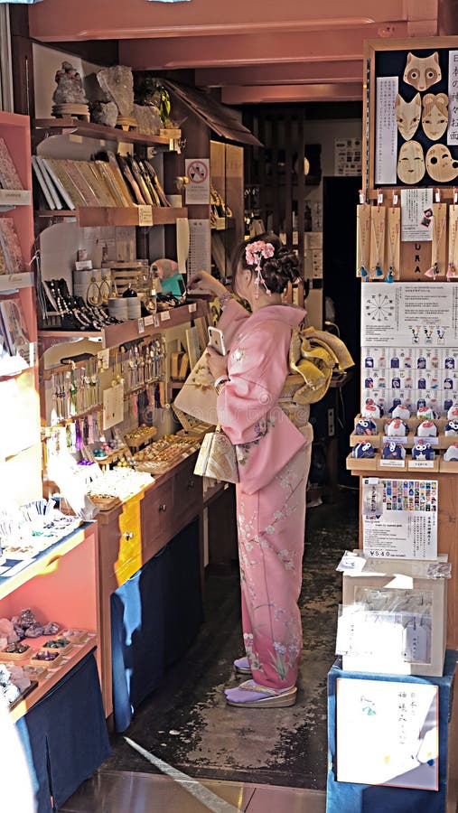 Una giovane donna che porta un kimono splendido in un deposito a Kyoto, Giappone immagini stock libere da diritti Una giovane donna che porta un kimono splendido in un deposito a Kyoto, Giappone immagini stock libere da diritti