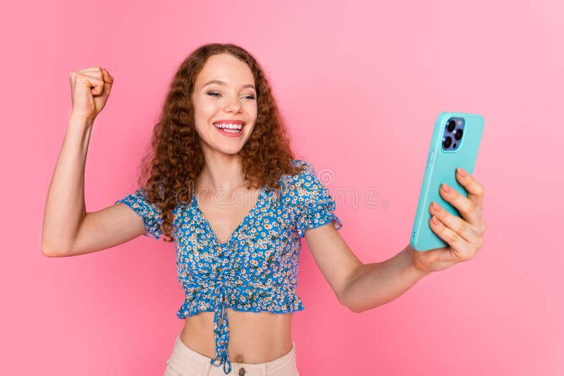 Una giovane donna eccitata che celebra la vittoria con lo smartphone in mano fotografia stock libera da diritti