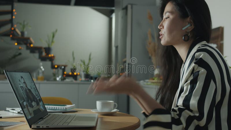 Una giovane donna felice che parla con un collega maschile usando il laptop per fare videochiamate online da casa