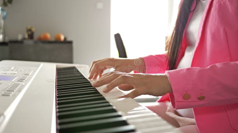 Una giovane donna incinta suona un pianoforte digitale bianco per il bambino.