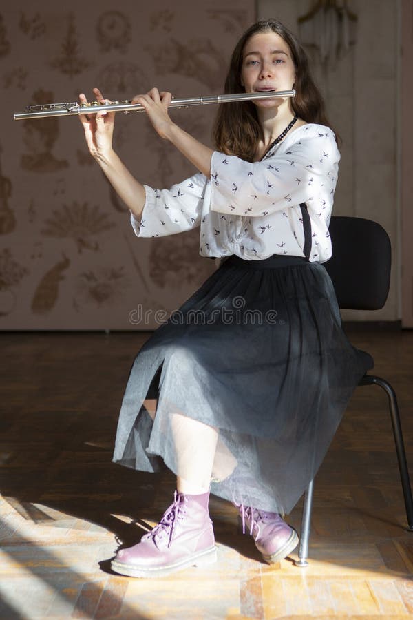 Una giovane donna splendida che si siede e che gioca la flauto fotografia stock libera da diritti Una giovane donna splendida che si siede e che gioca la flauto fotografia stock libera da diritti