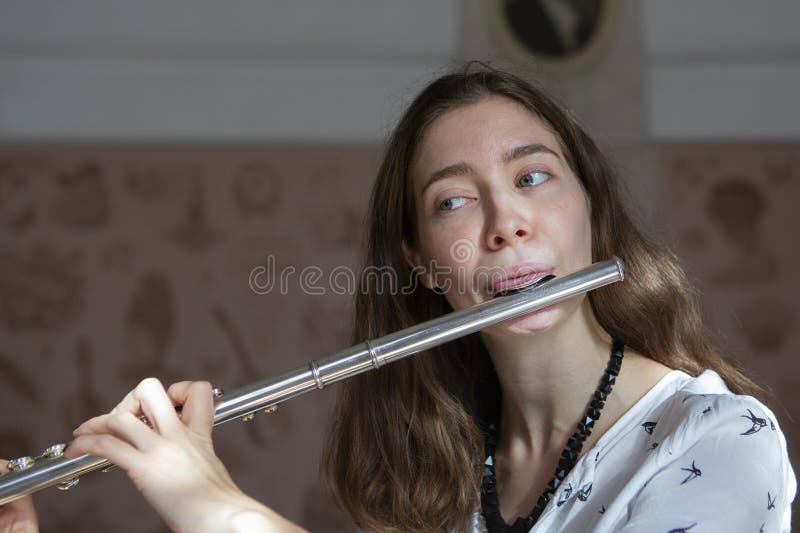 Una giovane donna splendida che si siede e che gioca la flauto immagini stock libere da diritti Una giovane donna splendida che si siede e che gioca la flauto immagini stock libere da diritti
