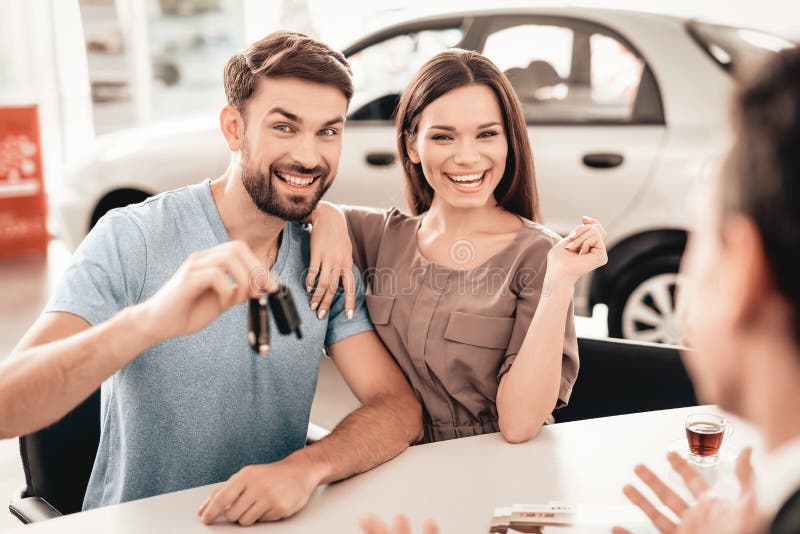 Una giovane famiglia è venuto alla sala d'esposizione dell'automobile a scegliere una nuova automobile fotografie stock Una giovane famiglia è venuto alla sala d'esposizione dell'automobile a scegliere una nuova automobile fotografie stock