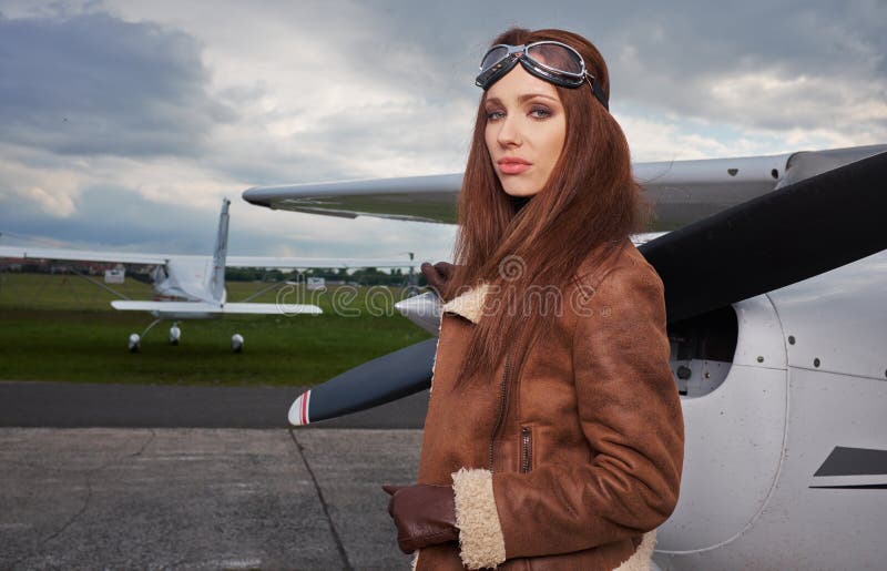 Una giovane pilota donna si trova accanto a un piccolo aereo da addestramento