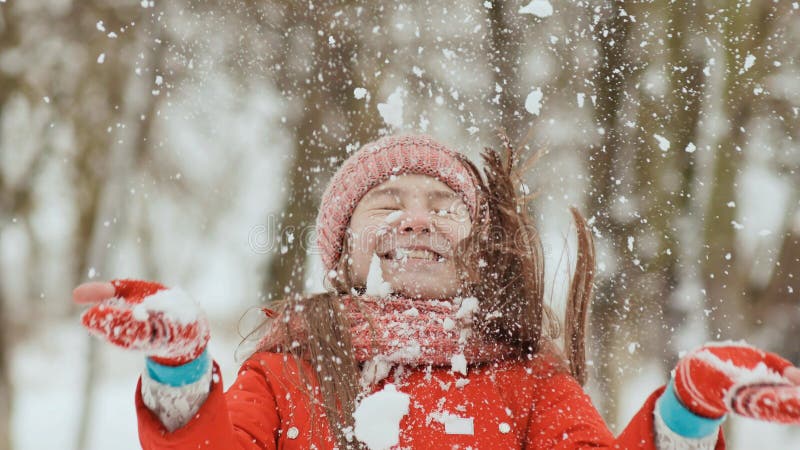 Una giovane scolara allegro getta una palla di neve e la rompe con una palma quando cade Emozioni di gioia Divertimento di invern