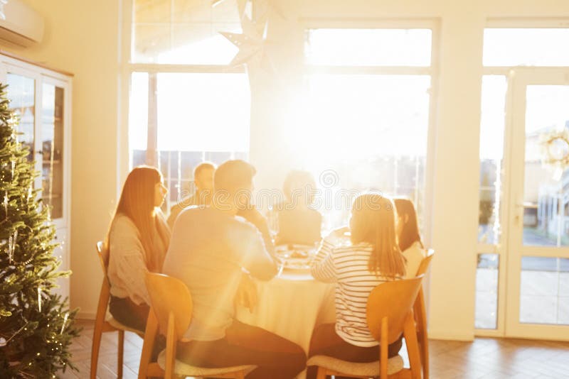 Una grande famiglia felice a una tavola rotonda festiva ai raggi del sole tramonto. nonna, nonna, madre padre e figlia adolescenti fotografia stock