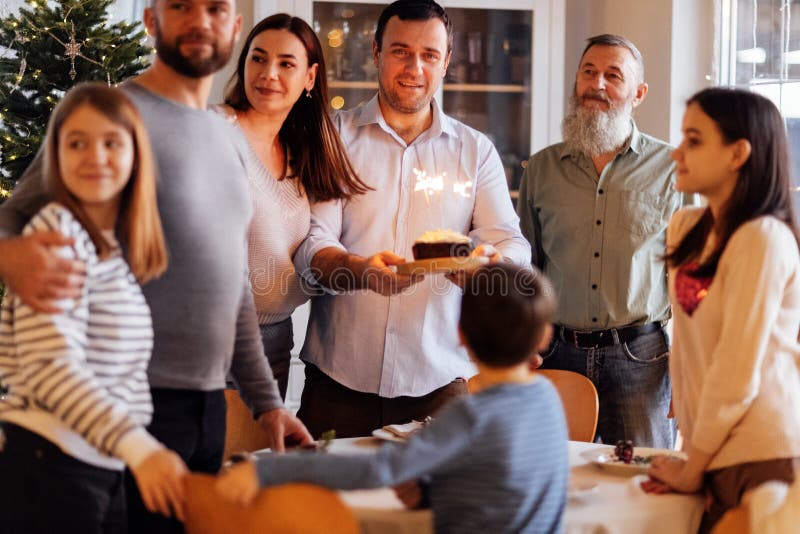 Una grande famiglia felice a un tavolo festivo a casa. un giovane attraente con una torta immagini stock libere da diritti