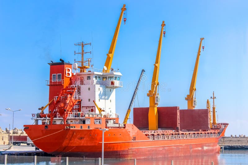 Una grande nave da carico a secco si trova al molo del porto in attesa del carico da caricare immagini stock libere da diritti Una grande nave da carico a secco si trova al molo del porto in attesa del carico da caricare immagini stock libere da diritti