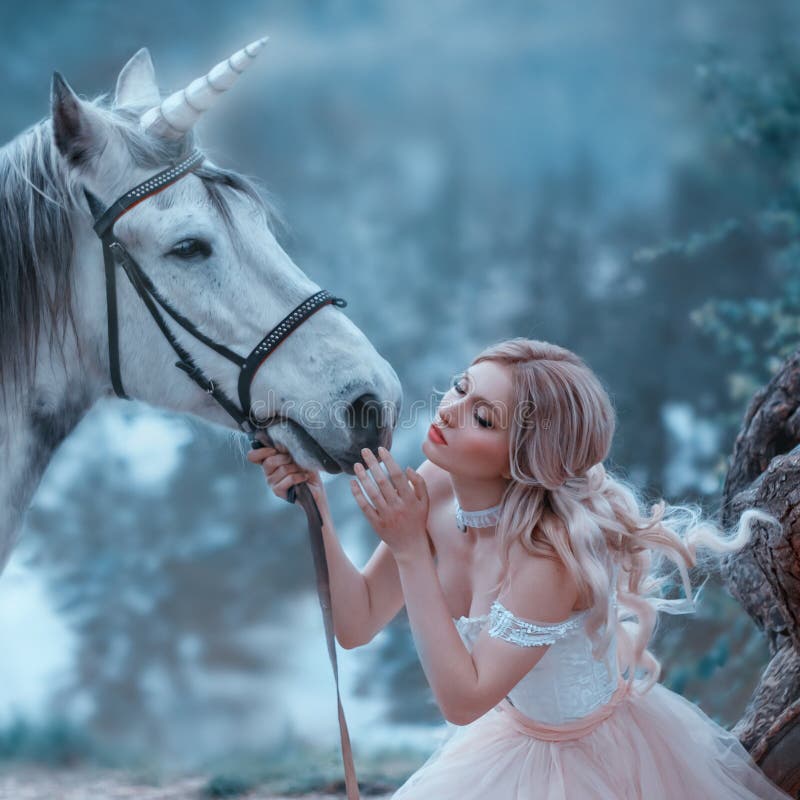 A fairy in a tender vintage dress hugs a unicorn. Fantastic magical, radiant horse. Background river and forest. Blonde girl with wavy hair - light elf. Artistic Photography. A fairy in a tender vintage dress hugs a unicorn. Fantastic magical, radiant horse. Background river and forest. Blonde girl with wavy hair - light elf. Artistic Photography