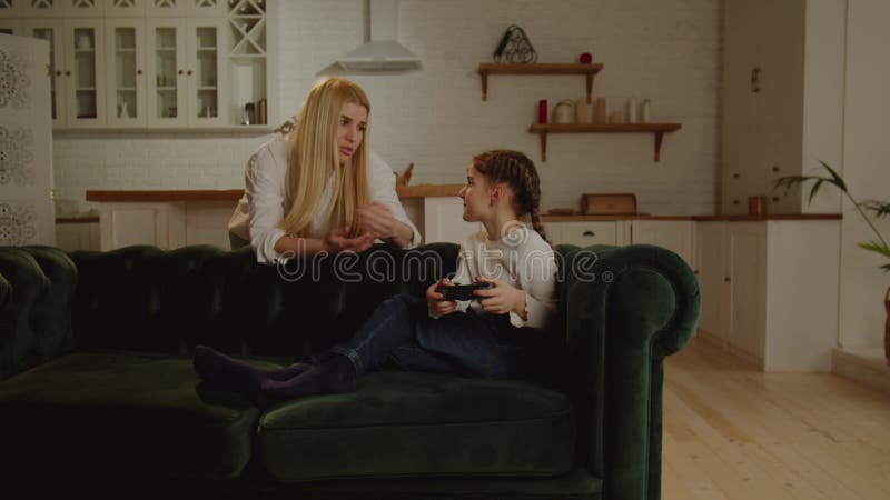 Una hija pequeña juega videojuegos y su madre le recordará que es hora de hacer su tarea. el límite de almacen de metraje de vídeo