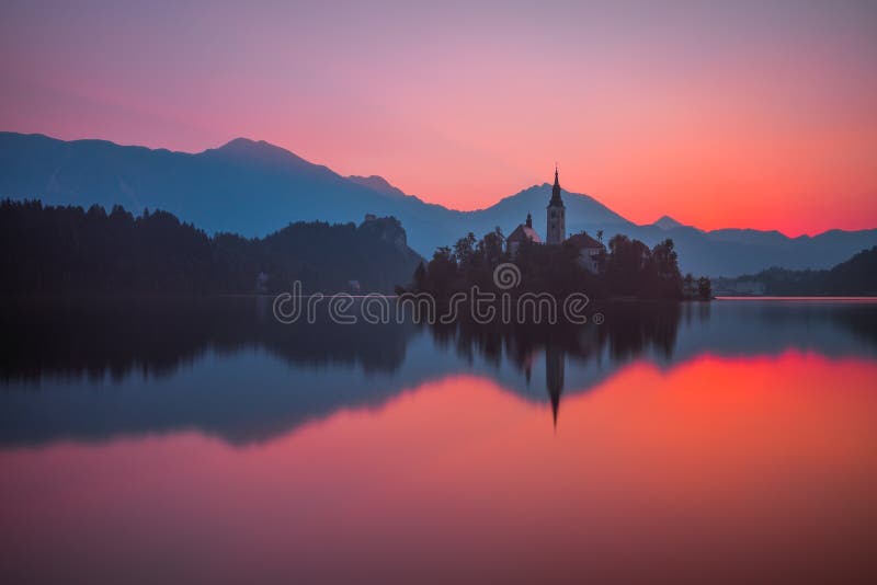 Una isla con la iglesia en el lago sangrado, Eslovenia en la salida del sol fotografía de archivo Una isla con la iglesia en el lago sangrado, Eslovenia en la salida del sol fotografía de archivo