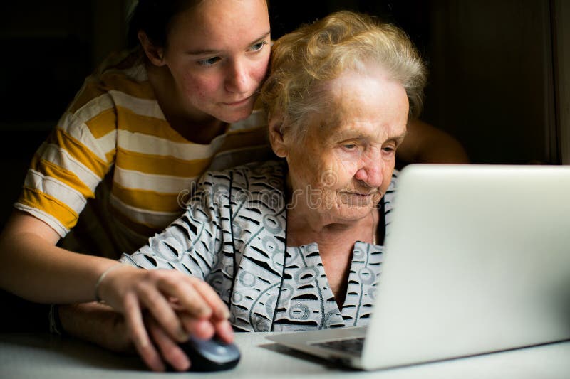 Una joven enseña a su abuela a usar una laptop fotografía de archivo