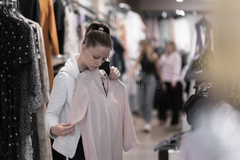 fácilmente electo convertible Una Joven Linda Mujer Con Ropa Blanca Compra Ropa En Una Tienda De  Comercios Intenta Con Una Camisa Blanca En El Estilo De Vida De Imagen de  archivo - Imagen de mirando,