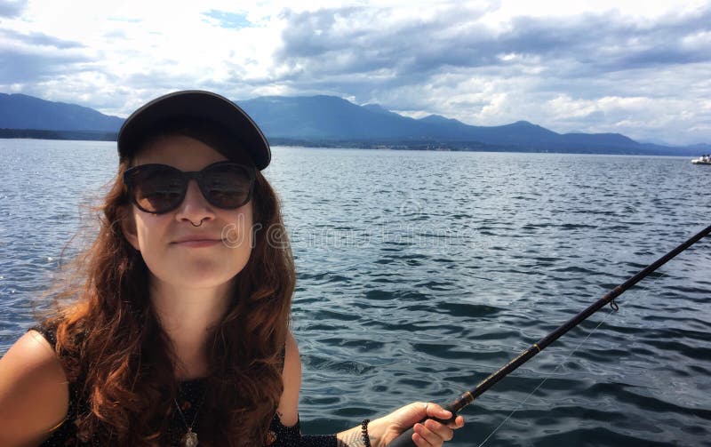 Una joven feliz y hermosa hipster sostiene una caña de pesca que pesca en el océano en un pequeño bote en las islas del Golfo imagen de archivo libre de regalías Una joven feliz y hermosa hipster sostiene una caña de pesca que pesca en el océano en un pequeño bote en las islas del Golfo imagen de archivo libre de regalías