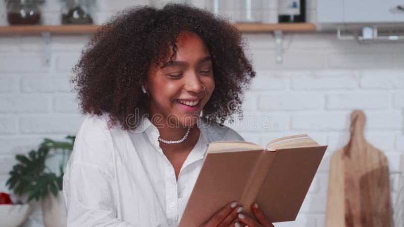 Una joven hispana de etnia hispana contenta leyendo libro riendo.