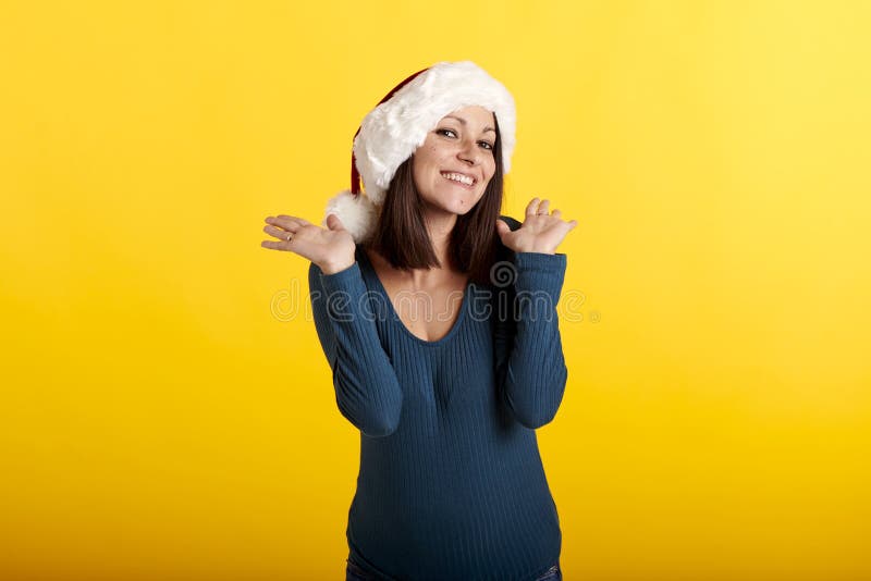 Una joven morena con una cara sorprendida y un sombrero de santa claus mirando la cámara imagenes de archivo