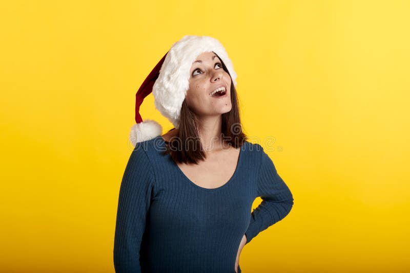 Una joven morena con un sombrero de santa claus mirando hacia arriba. imagen de archivo libre de regalías