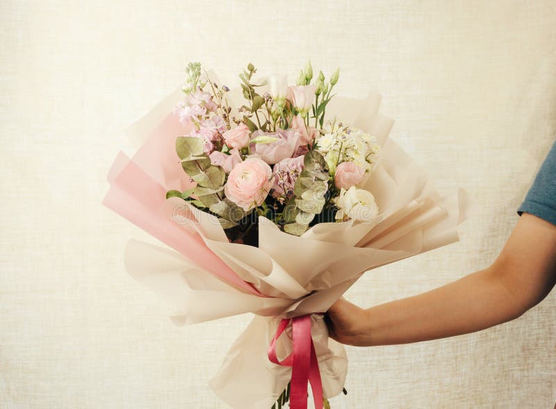 Una joven sostiene un gran y hermoso ramo de rosas frescas eustoma matiola freesia eucalyptus hidrangea en rosa delicado fotos de archivo