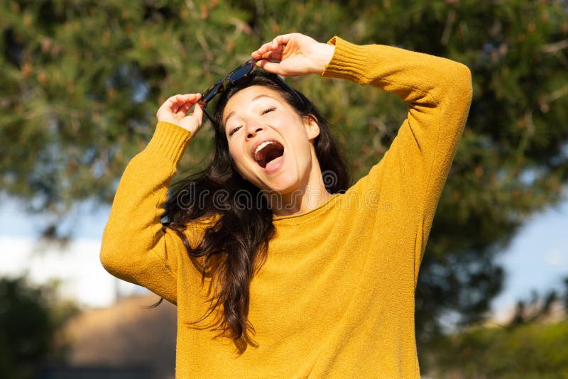 Una joven y emocionada mujer china parada afuera y riendo foto de archivo libre de regalías