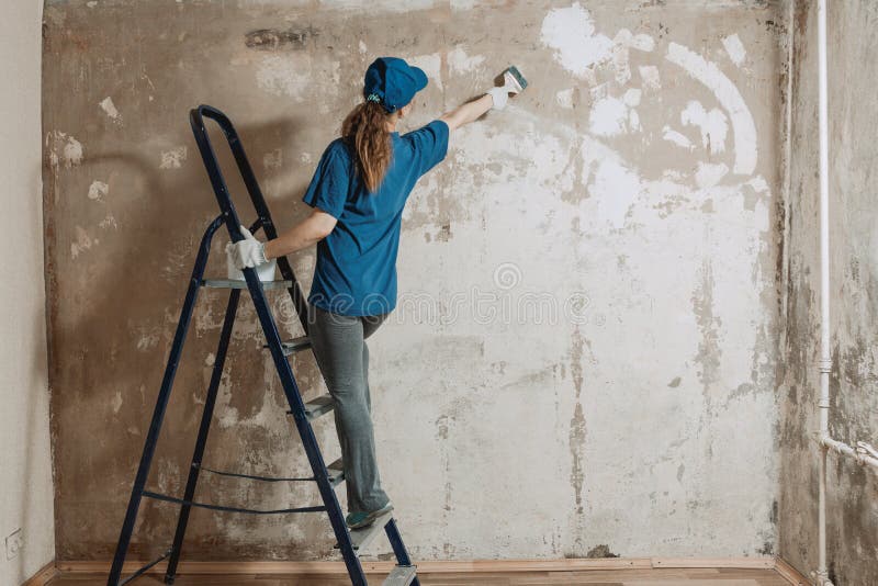 Una Jovencita Con Trabajo Azul Está Haciendo Reparaciones En Casa. Pinza La Base Para Pintar Foto de archivo - Imagen de cepillo, sitio: 174934240