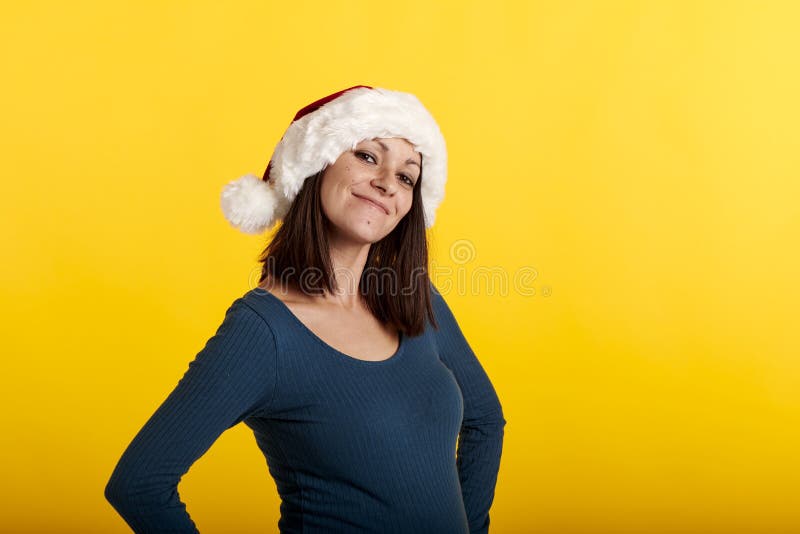 Una jovencita sonriente con un sombrero de Papá Noel en un fondo amarillo fotografía de archivo libre de regalías