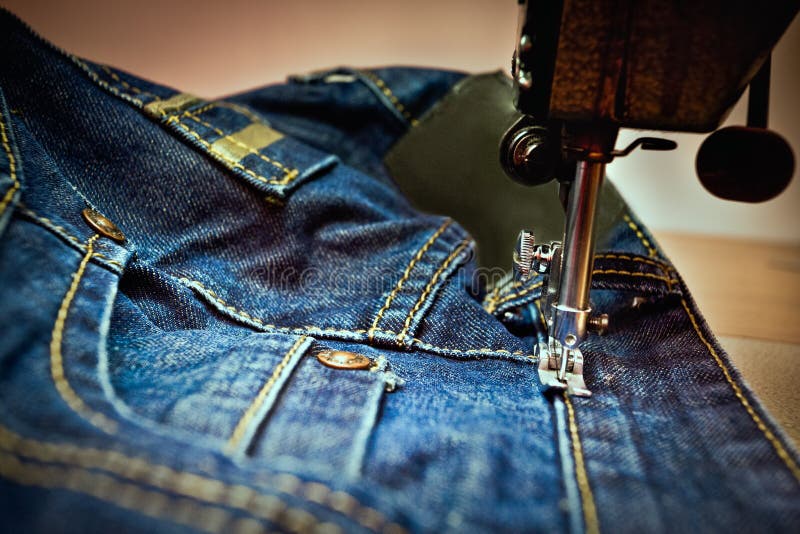 Una macchina da cucire che cuce dei jeans immagini stock