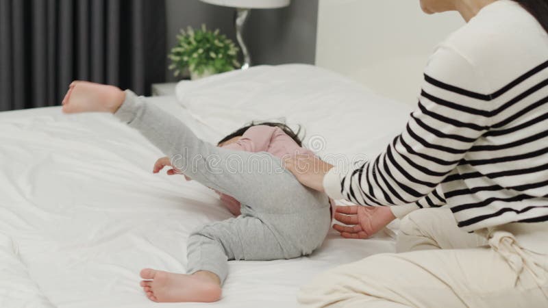 Una madre alegre y una niña pequeña jugando en la cama almacen de video