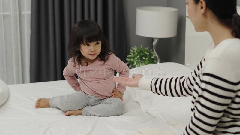 Una madre alegre y una niña pequeña jugando en la cama almacen de video