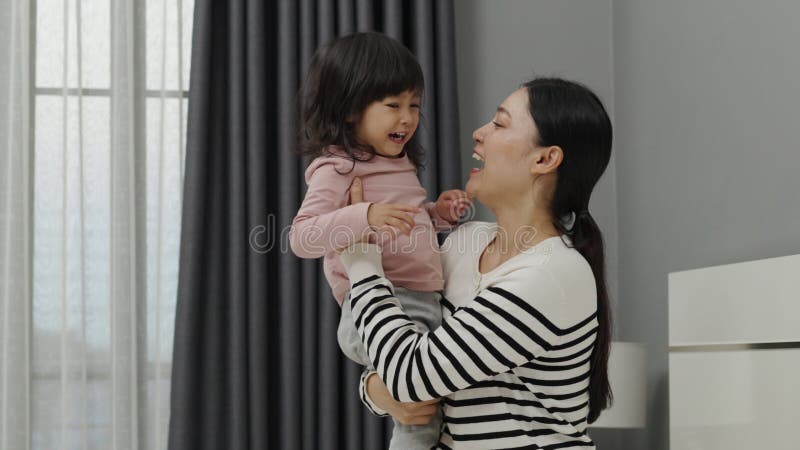 Una madre alegre y una niña pequeña jugando en la cama almacen de metraje de vídeo