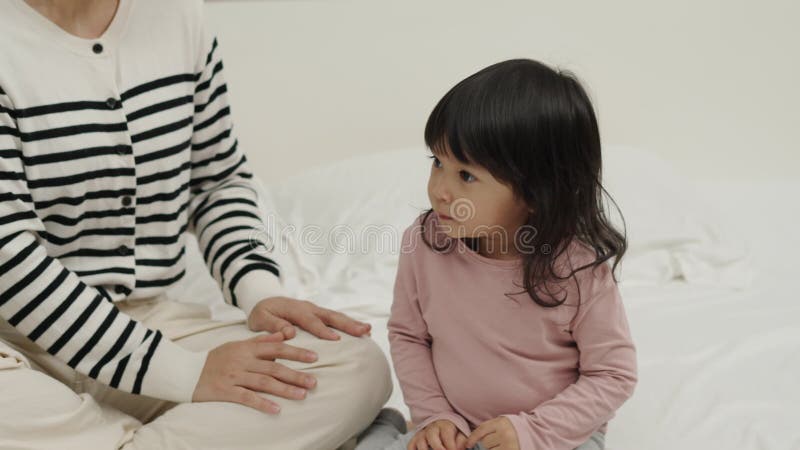 Una madre alegre y una niña pequeña jugando en la cama metrajes