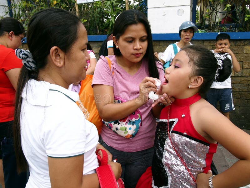 Una madre aplica el lápiz labial y compone en su niño que el ` s un participante en un desfile durante el festival de Sumaka en l imágenes de archivo libres de regalías Una madre aplica el lápiz labial y compone en su niño que el ` s un participante en un desfile durante el festival de Sumaka en l imágenes de archivo libres de regalías