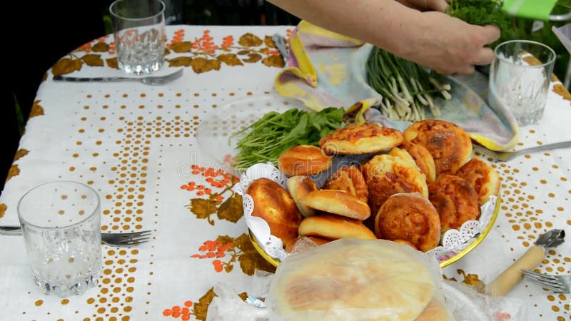 Una mano delle donne mette un tavolo coperto da una tovaglia per una cena di famiglia all'aperto nel giardino espone cipolle verdi