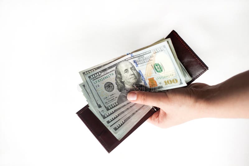 Una mano femenina que lleva a cabo una cartera por completo de billetes de dólar del nuevo ciento aislados sobre un fondo blanco fotografía de archivo Una mano femenina que lleva a cabo una cartera por completo de billetes de dólar del nuevo ciento aislados sobre un fondo blanco fotografía de archivo