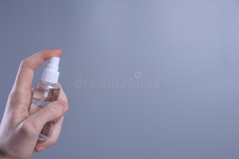 Una mano mantiene e spruzza uno spray disinfettante per disinfettare varie superfici che la gente tocca il gel antisettico anticor