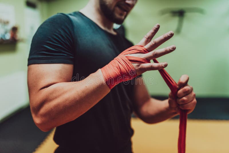 Una mano maschile di pugile o pugile con bende di pugilato rosso prima della rissa o dell'addestramento in palestra sportiva. immagine stock