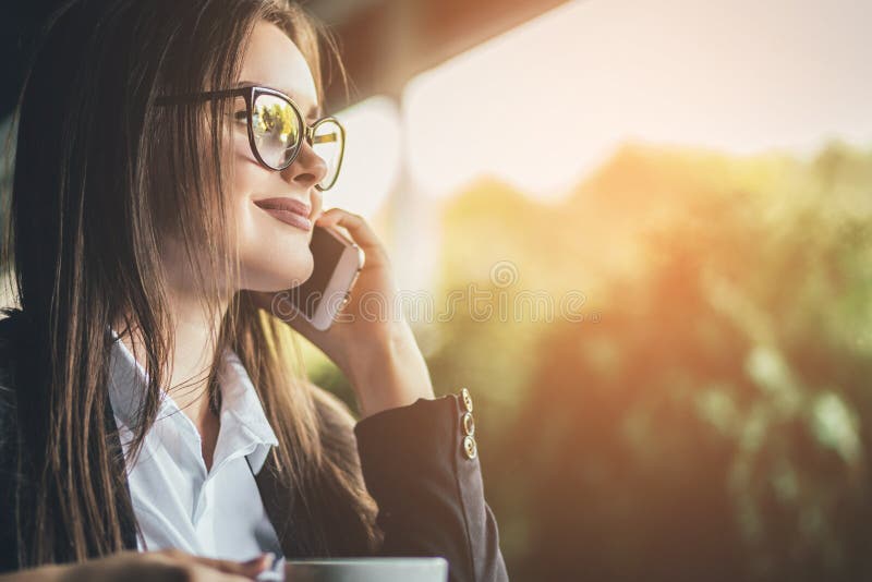 Una mattina un bello caffè della bevanda della donna elegante al caffè all'aperto mentre chiamando i suoi amici con il telefono e fotografia stock libera da diritti Una mattina un bello caffè della bevanda della donna elegante al caffè all'aperto mentre chiamando i suoi amici con il telefono e fotografia stock libera da diritti