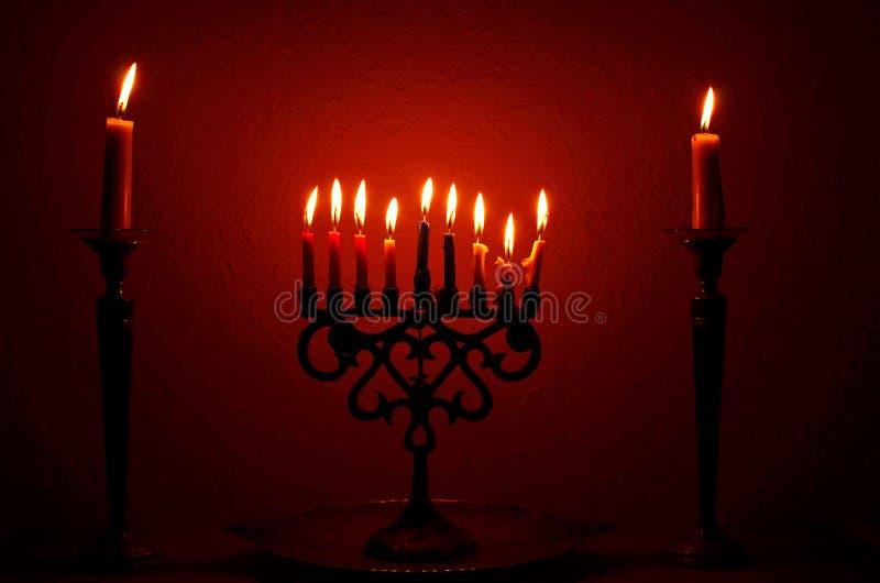 Una menorah piena di candele accese e affiancata da due candele per la festa ebraica, Hanukkah immagini stock Una menorah piena di candele accese e affiancata da due candele per la festa ebraica, Hanukkah immagini stock