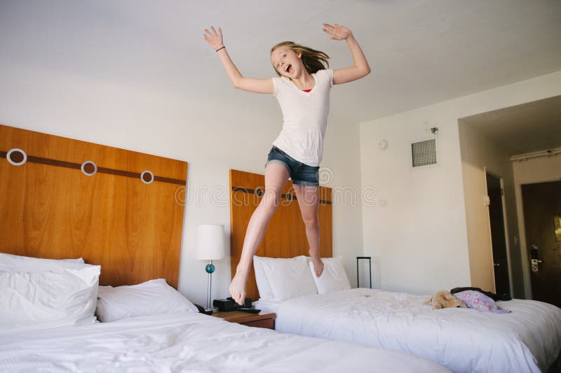 Una muchacha adolescente rubia que salta en camas en un hotel. fotos de archivo libres de regalías Una muchacha adolescente rubia que salta en camas en un hotel. fotos de archivo libres de regalías