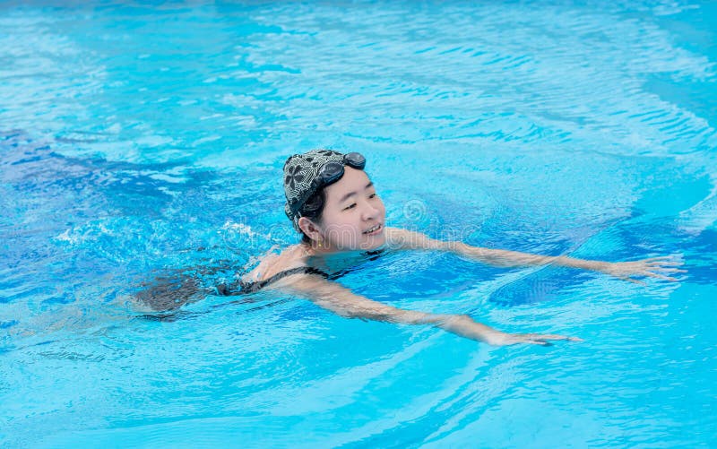 Una muchacha asiática está nadando en la piscina fotografía de archivo libre de regalías Una muchacha asiática está nadando en la piscina fotografía de archivo libre de regalías
