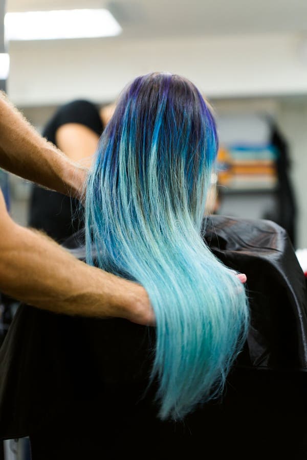 Una muchacha con el pelo teñido que se sienta en una silla en el estudio del salón de belleza Trabajo sobre la demostración imagen de archivo Una muchacha con el pelo teñido que se sienta en una silla en el estudio del salón de belleza Trabajo sobre la demostración imagen de archivo
