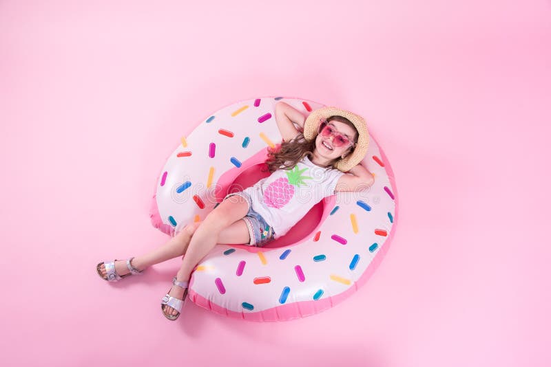 Una muchacha del peque?o ni?o que miente en un c?rculo inflable del bu?uelo Fondo rosado Visi?n superior Concepto del verano fotos de archivo Una muchacha del peque?o ni?o que miente en un c?rculo inflable del bu?uelo Fondo rosado Visi?n superior Concepto del verano fotos de archivo