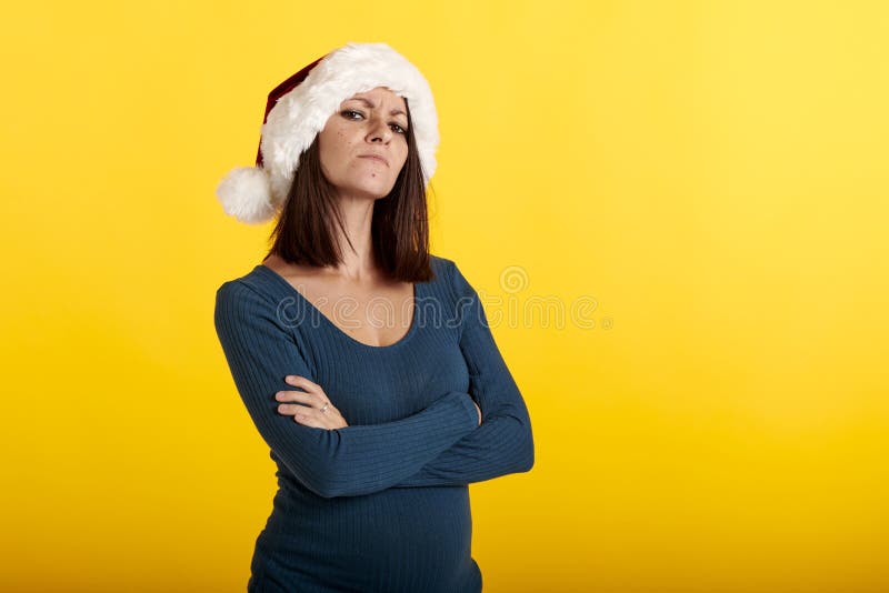 Una muchacha enfadada con un sombrero de Papá Noel de color amarillo fotografía de archivo libre de regalías