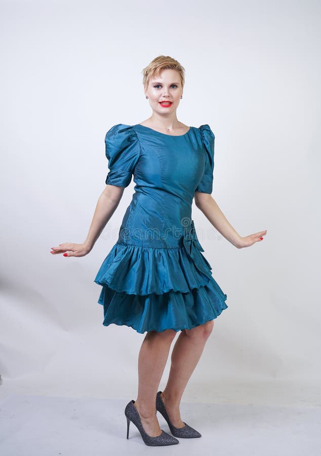 Una muchacha hermosa con una figura del tamaño extra grande vestida en un vestido retro lindo y soportes de la moda en un fondo b imagen de archivo Una muchacha hermosa con una figura del tamaño extra grande vestida en un vestido retro lindo y soportes de la moda en un fondo b imagen de archivo