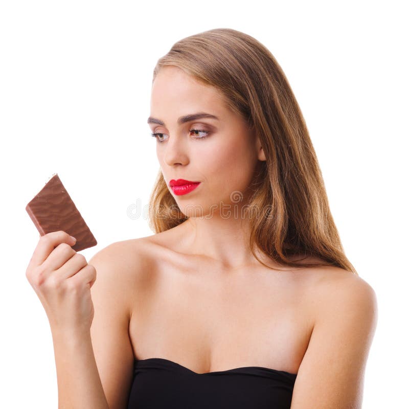 Una muchacha morena hermosa en un vestido negro sostiene un chocolate y lo mira Aislado foto de archivo Una muchacha morena hermosa en un vestido negro sostiene un chocolate y lo mira Aislado foto de archivo
