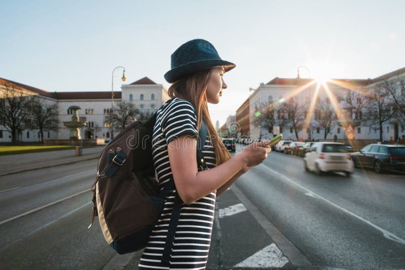 Una muchacha o un estudiante turística con una mochila camina a lo largo de una calle en Munich fotografía de archivo Una muchacha o un estudiante turística con una mochila camina a lo largo de una calle en Munich fotografía de archivo