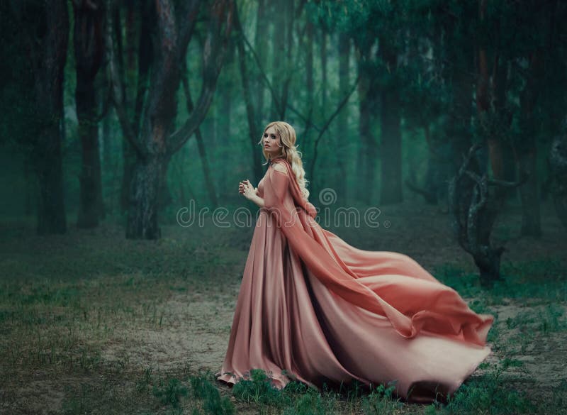 Una muchacha rubia misteriosa en un vestido rosado largo con un tren y un impermeable que agita en el viento Las hojas del mago imagenes de archivo Una muchacha rubia misteriosa en un vestido rosado largo con un tren y un impermeable que agita en el viento Las hojas del mago imagenes de archivo